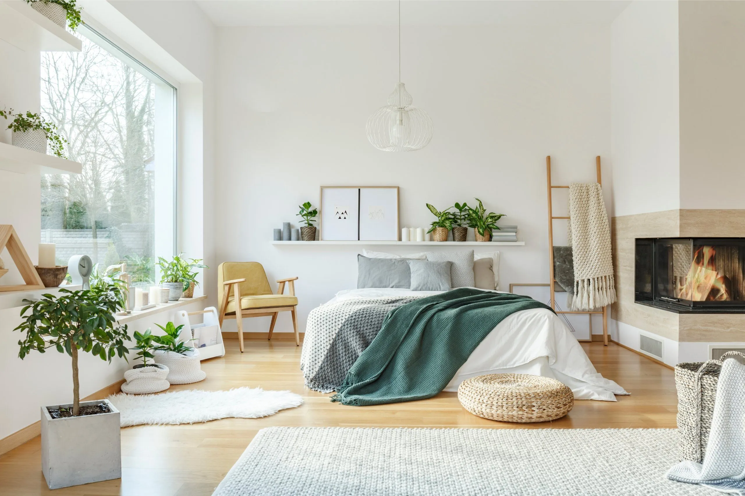 Heller, menschenleerer Wohn- und Schlafraum mit großem Fenster und Kamin