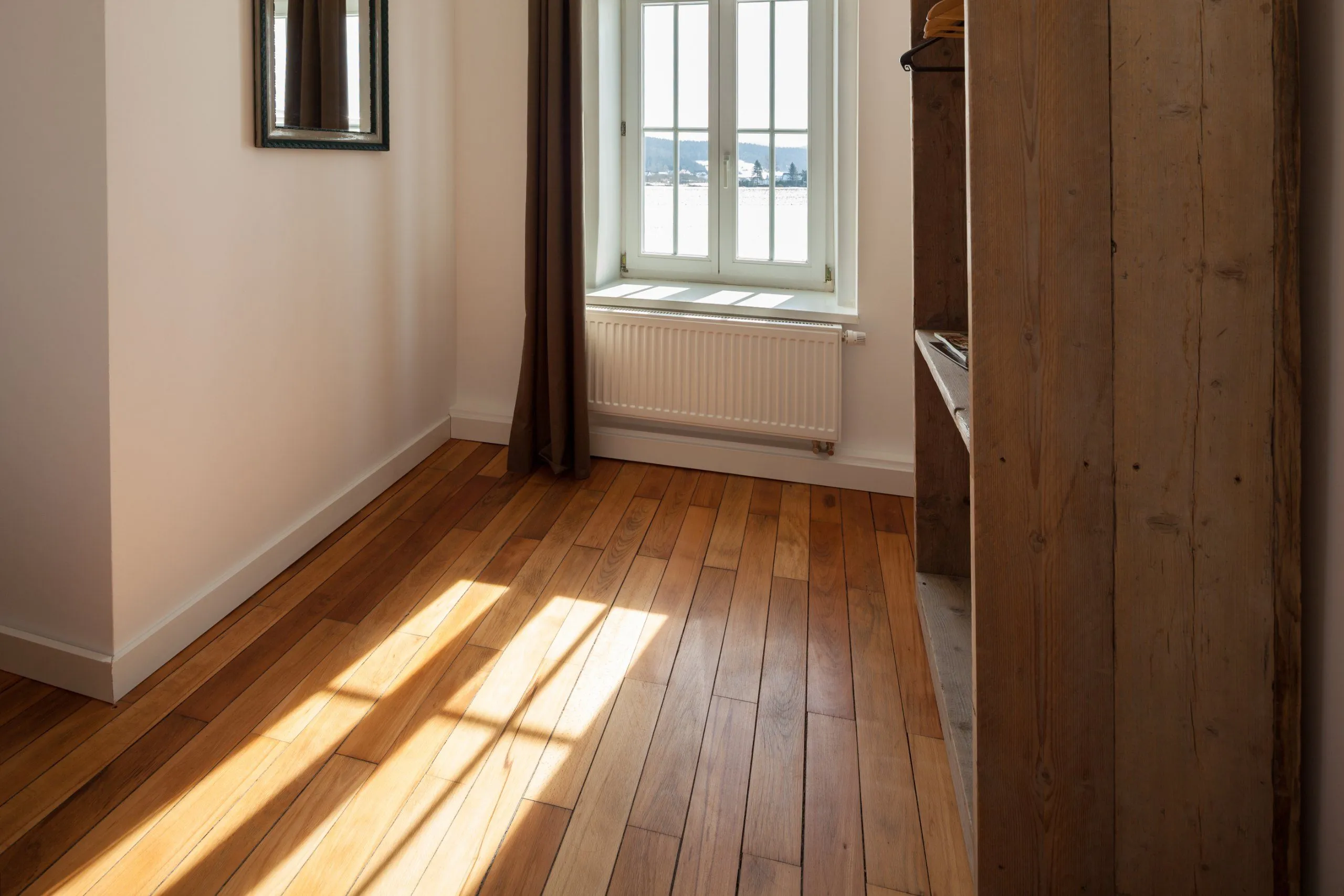 Leerer Raum mit Dielenboden, Fenster und offener Holztür