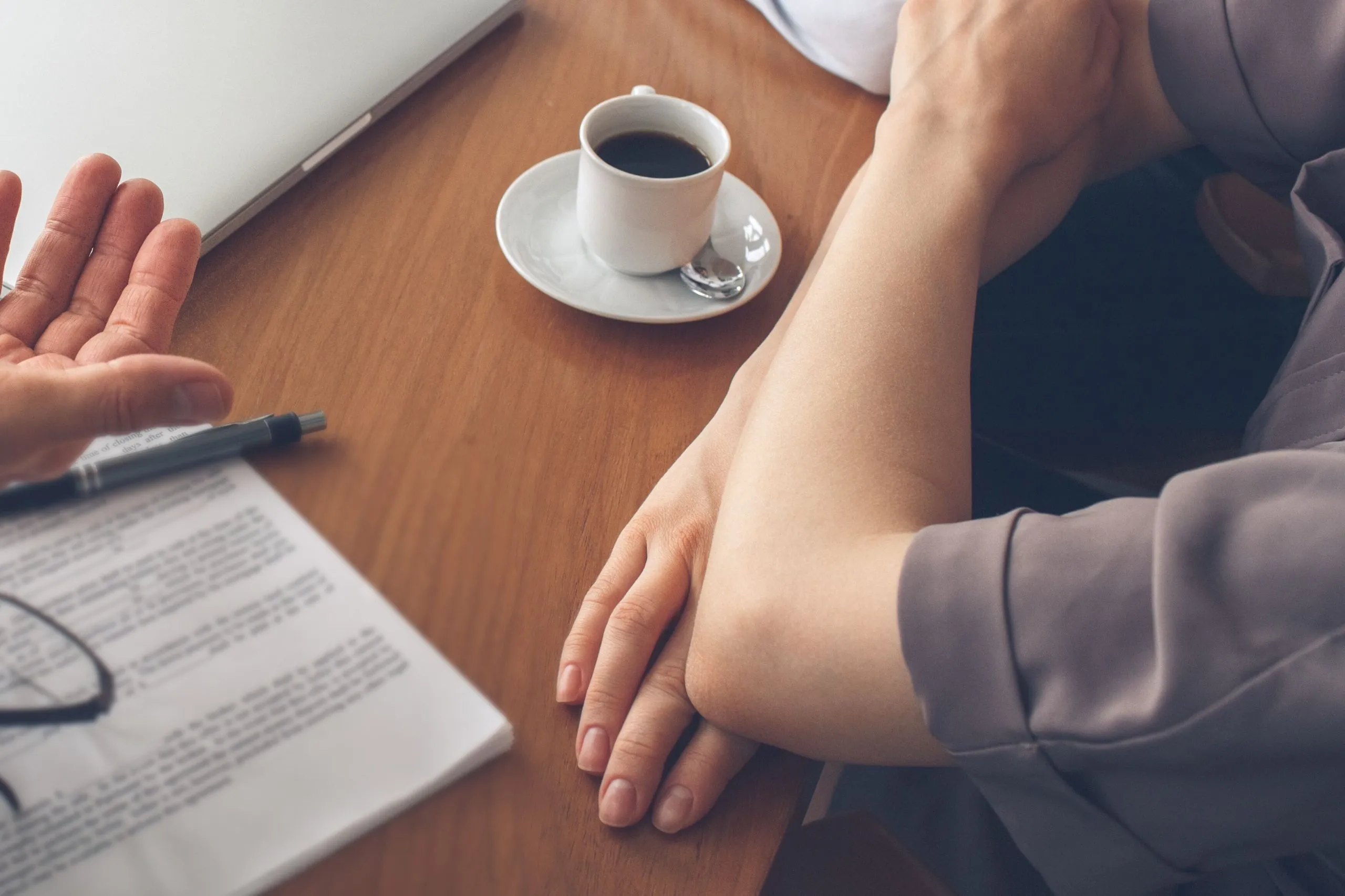 Zwei Menschen am Tisch, Unterlagen und Kaffee zwischen ihnen Zwei Menschen am Tisch, Unterlagen und Kaffee zwischen ihnen